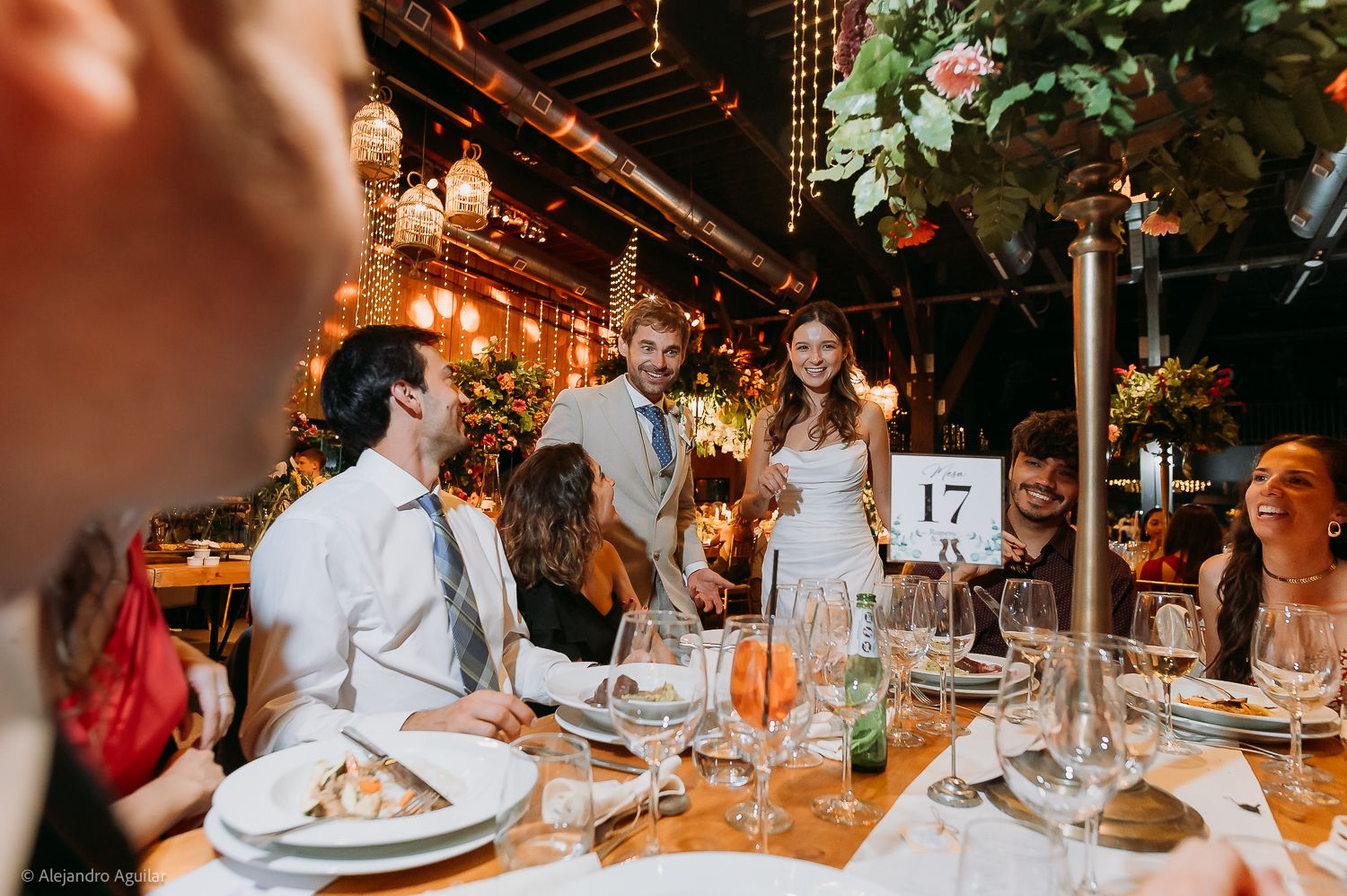 Bride and groom share a joyful moment at table 17 during an elegant indoor wedding reception with warm lighting.