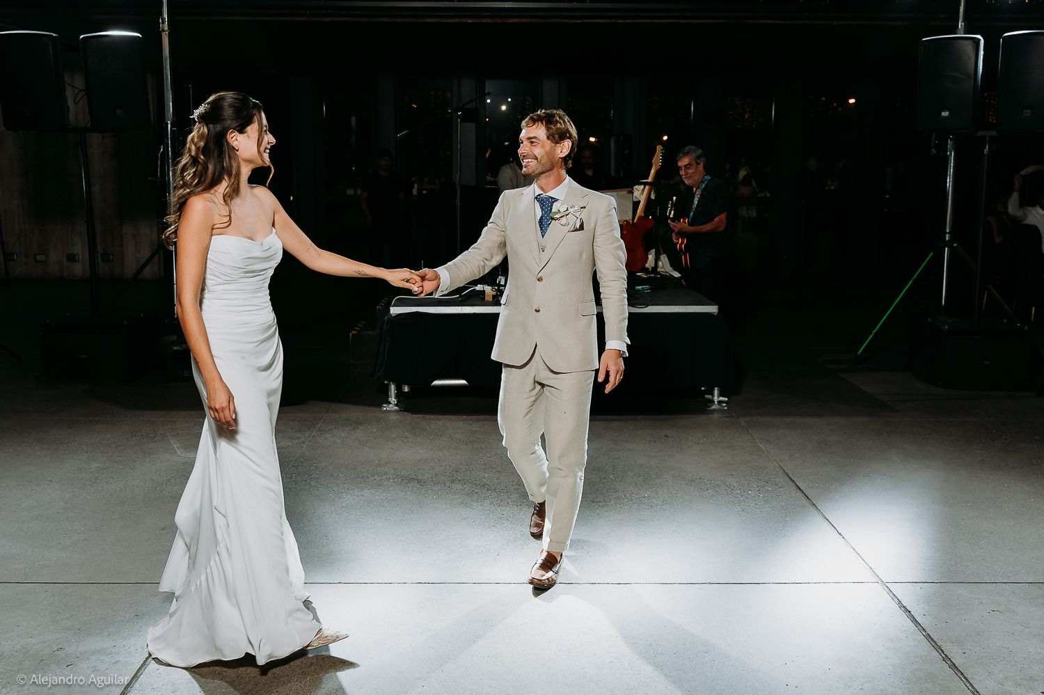 Bride and groom share their first dance on a white dance floor at an elegant wedding reception.