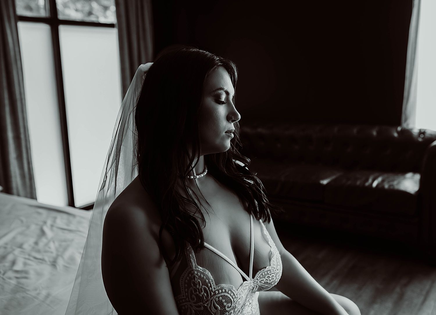 woman sits on couch with veil on by Wisconsin boudoir photographer