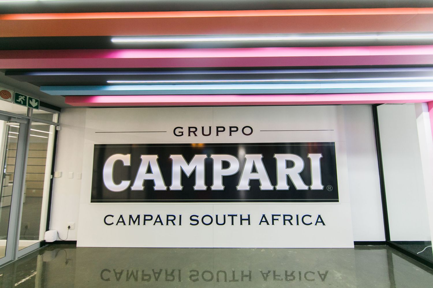 Gruppo Campari South Africa logo displayed on a white wall with colorful neon light streaks above.