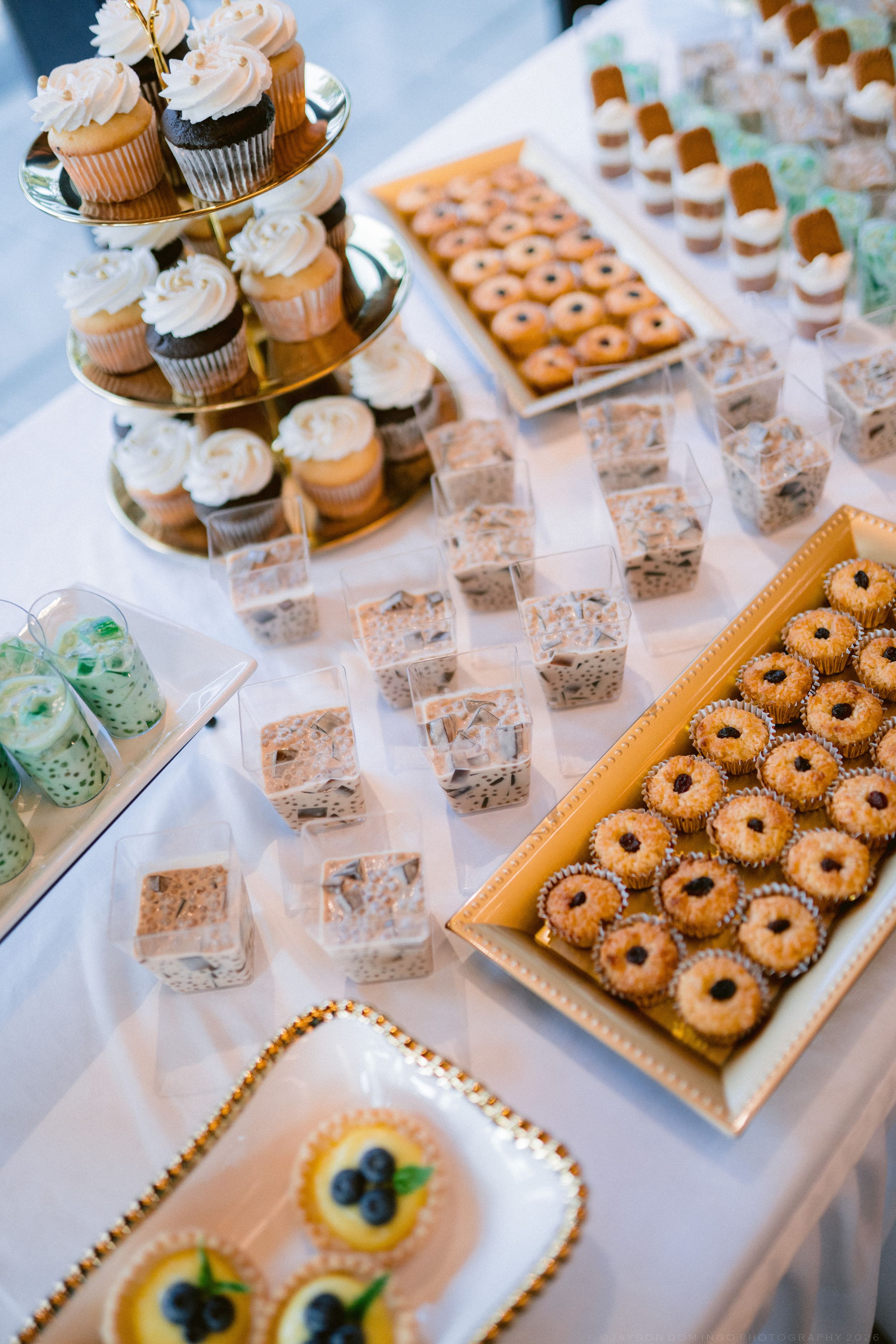 Elegant wedding dessert table with cupcakes, mini donuts, and assorted sweet treats.