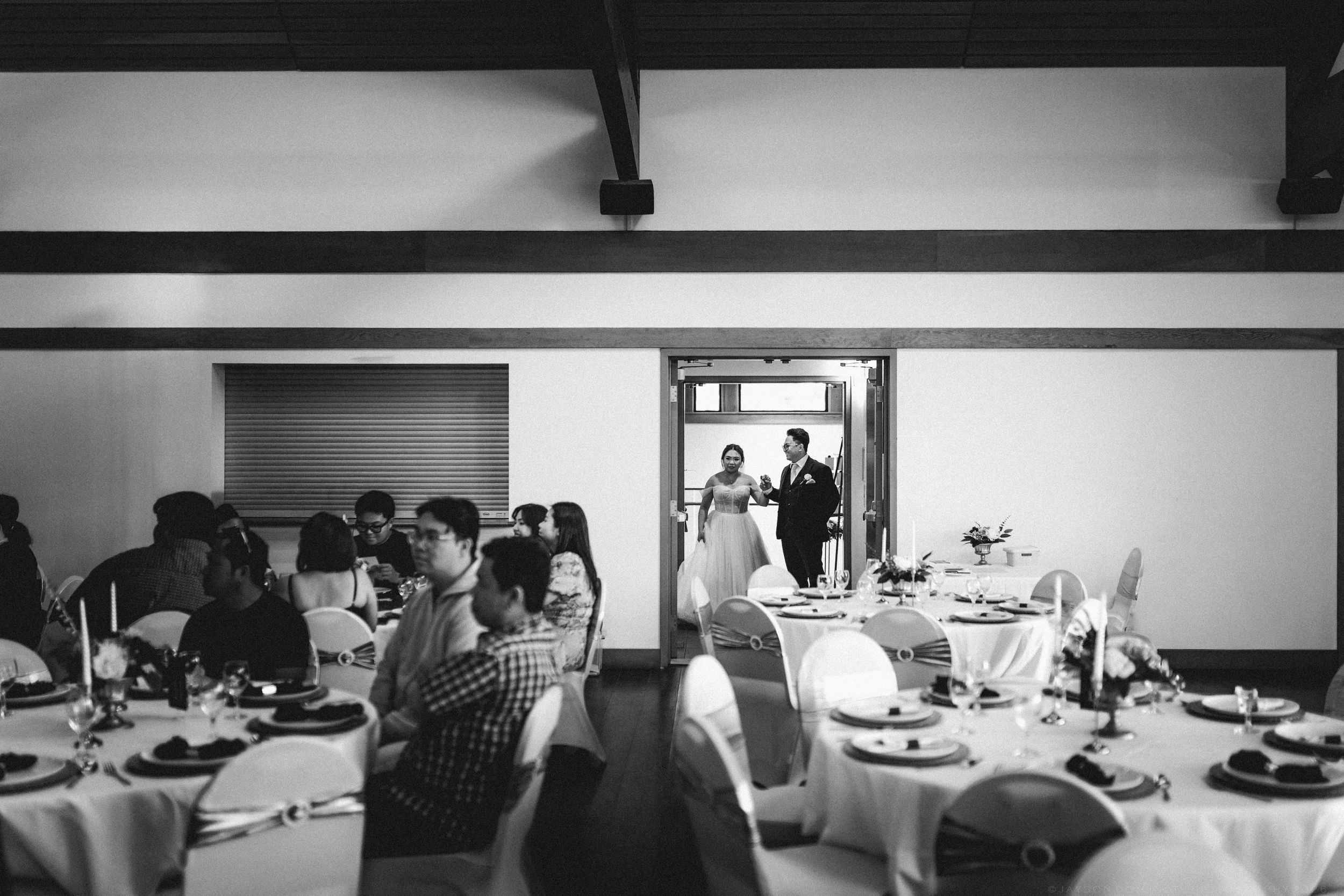 Black and white photo of a bride and groom entering a wedding reception hall.