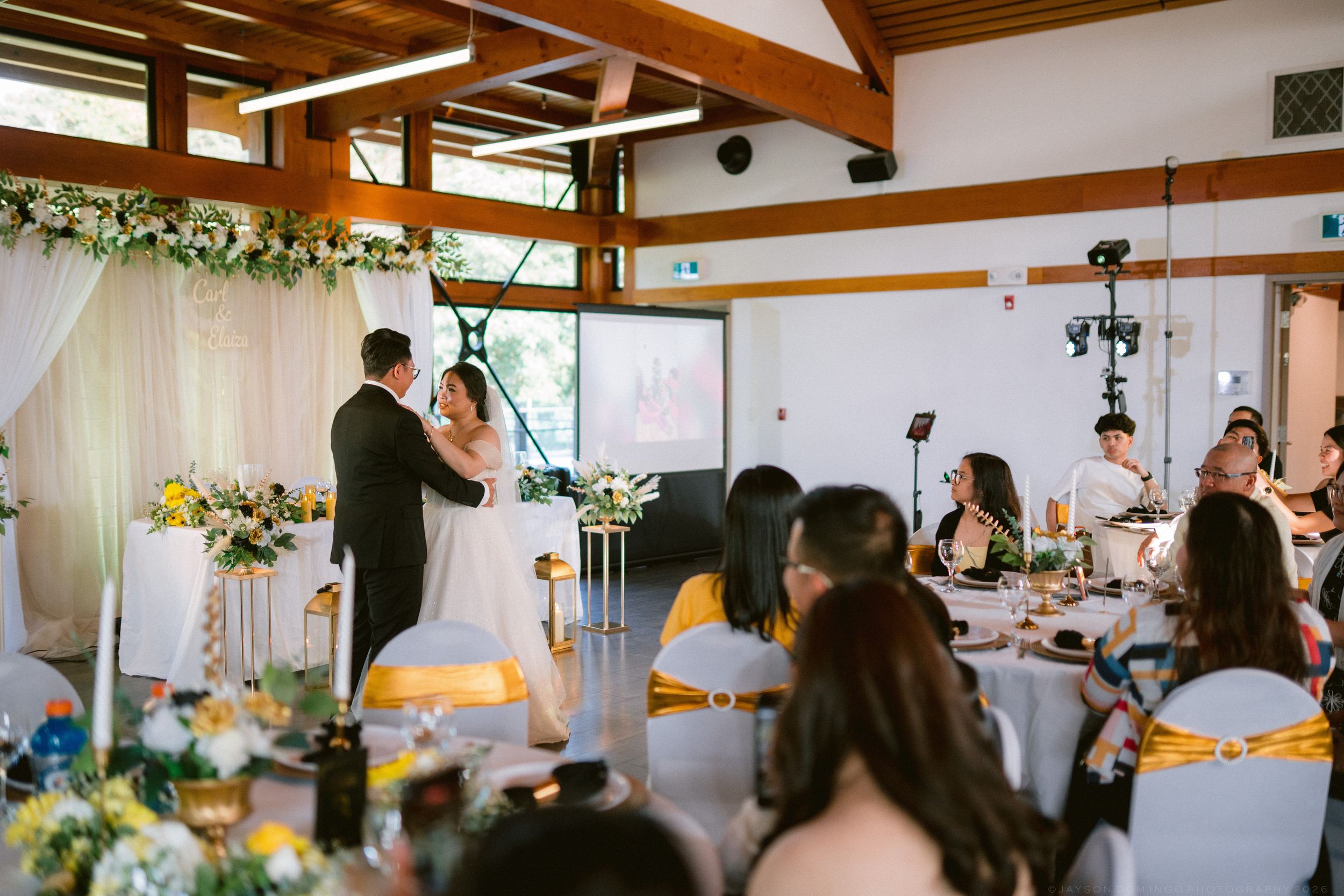 Bride and groom share first dance at elegant indoor wedding reception.