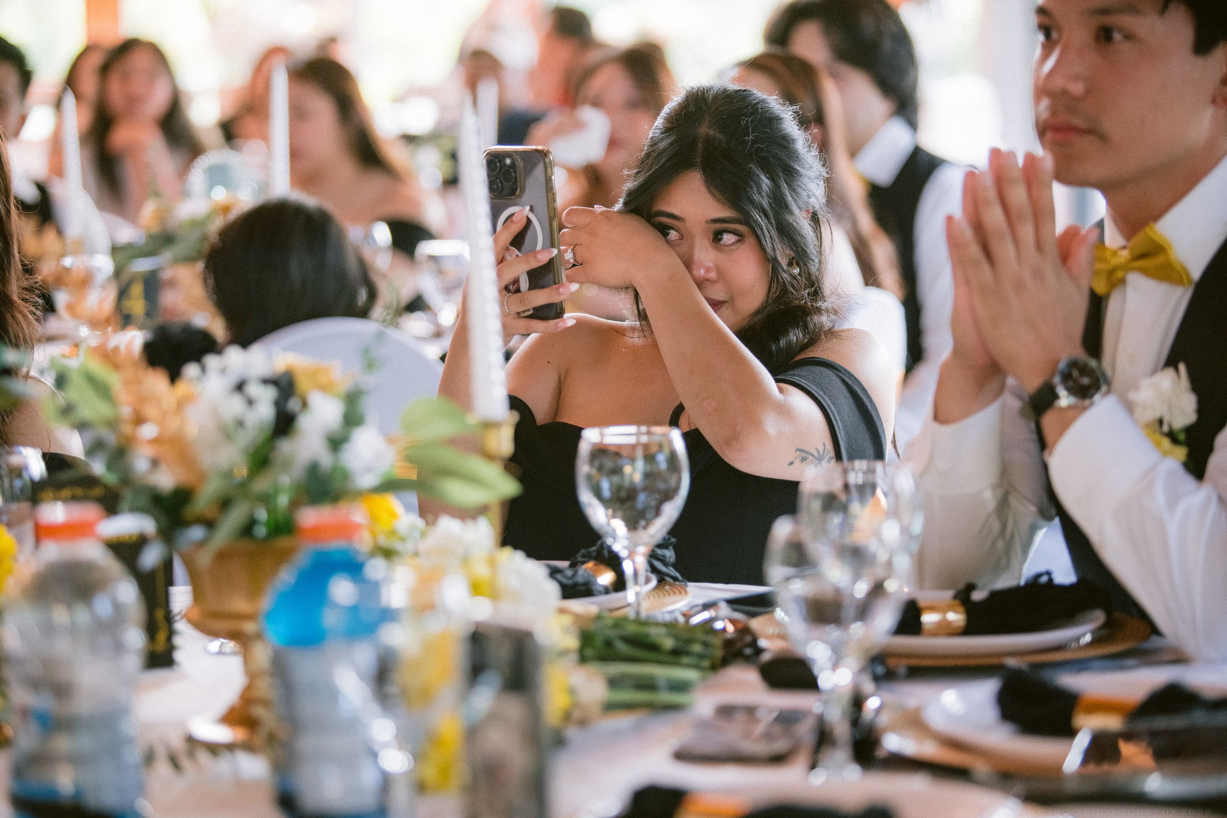 Wedding guest photographs reception on smartphone at elegantly decorated table.