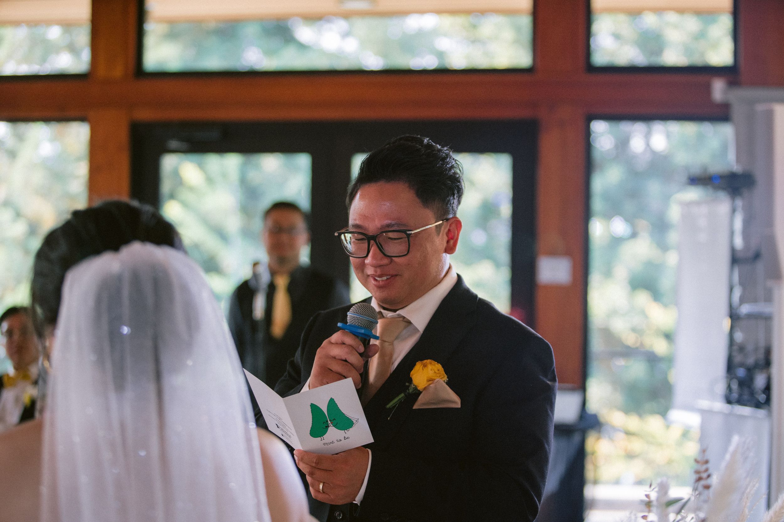 A groom reads his wedding vows at the altar holding a microphone during the ceremony.