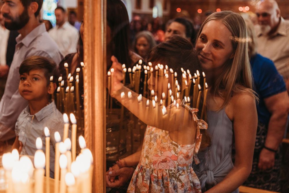 Children and adults lighting candles at a church altar during a religious ceremony.
