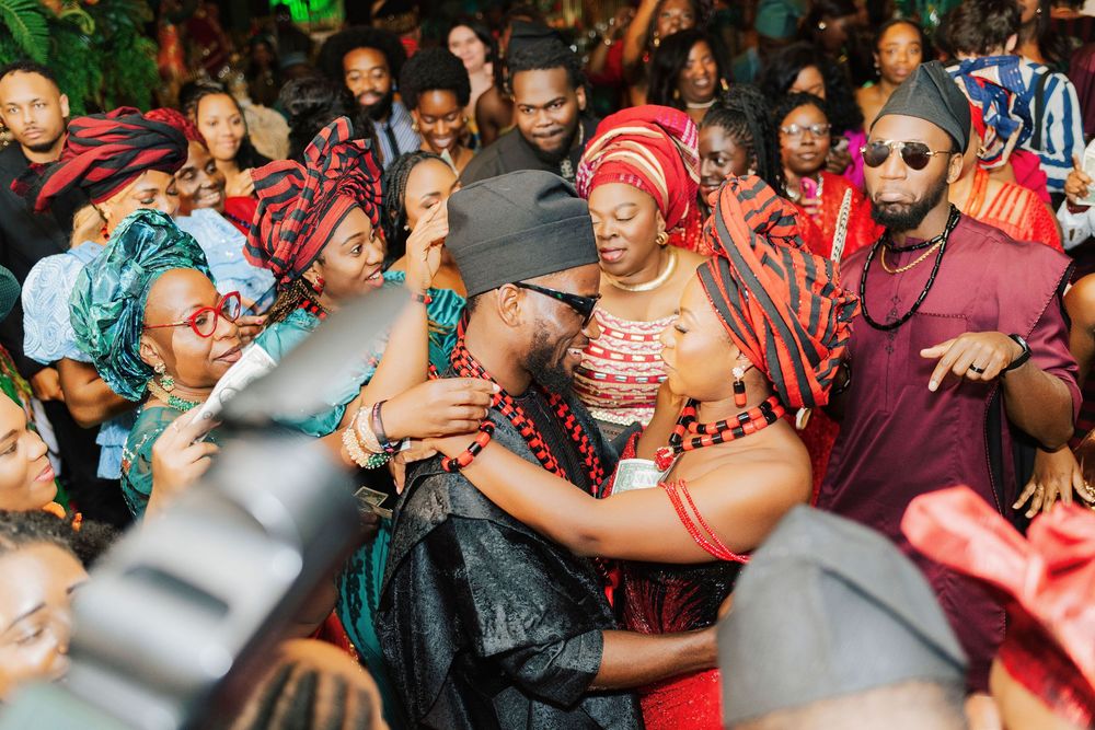 Vibrant African traditional wedding celebration with guests dancing in colorful red and black attire at a festive ceremony.