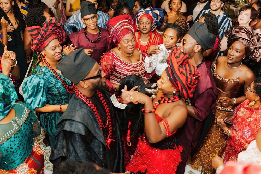 Vibrant Nigerian traditional wedding celebration with guests in colorful cultural attire and red coral beads.