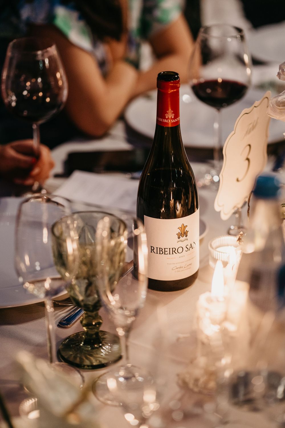 Ribeiro Santo red wine bottle on elegant candlelit dinner table with wine glasses at a formal event.