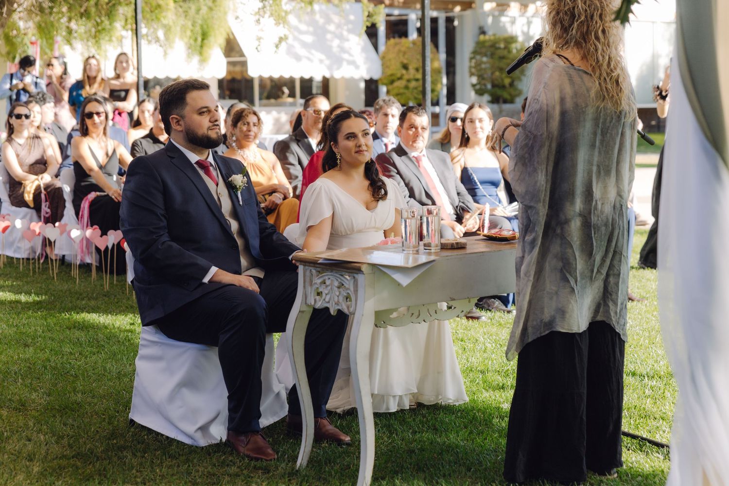 Bride and groom listening attentively to officiant during elegant outdoor garden wedding ceremony.