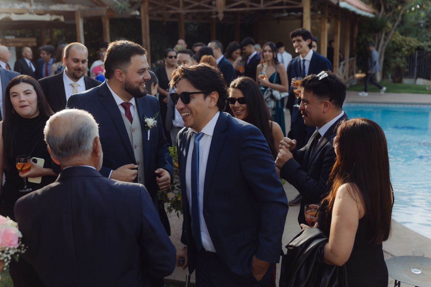 Wedding guests mingling and socializing outdoors near a pool at an elegant wedding reception.