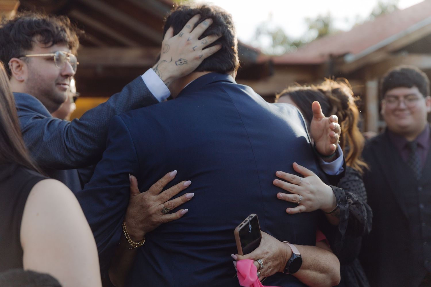 Emotional wedding guests sharing warm hugs during an outdoor wedding celebration.