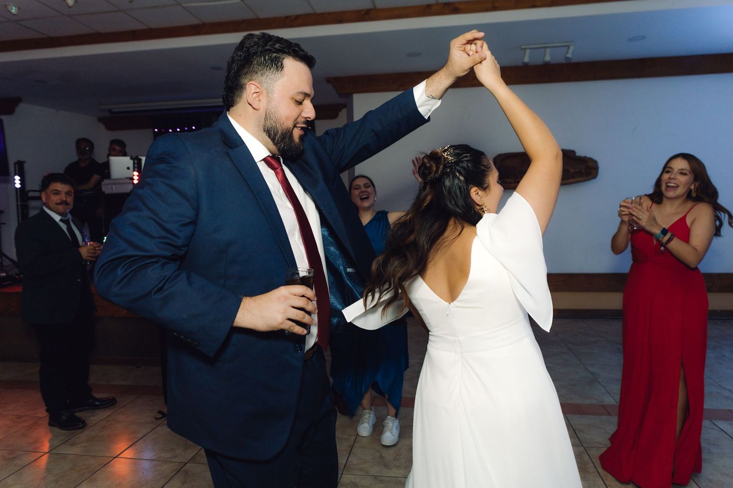 Groom twirls bride in white dress on the dance floor at a fun wedding reception.
