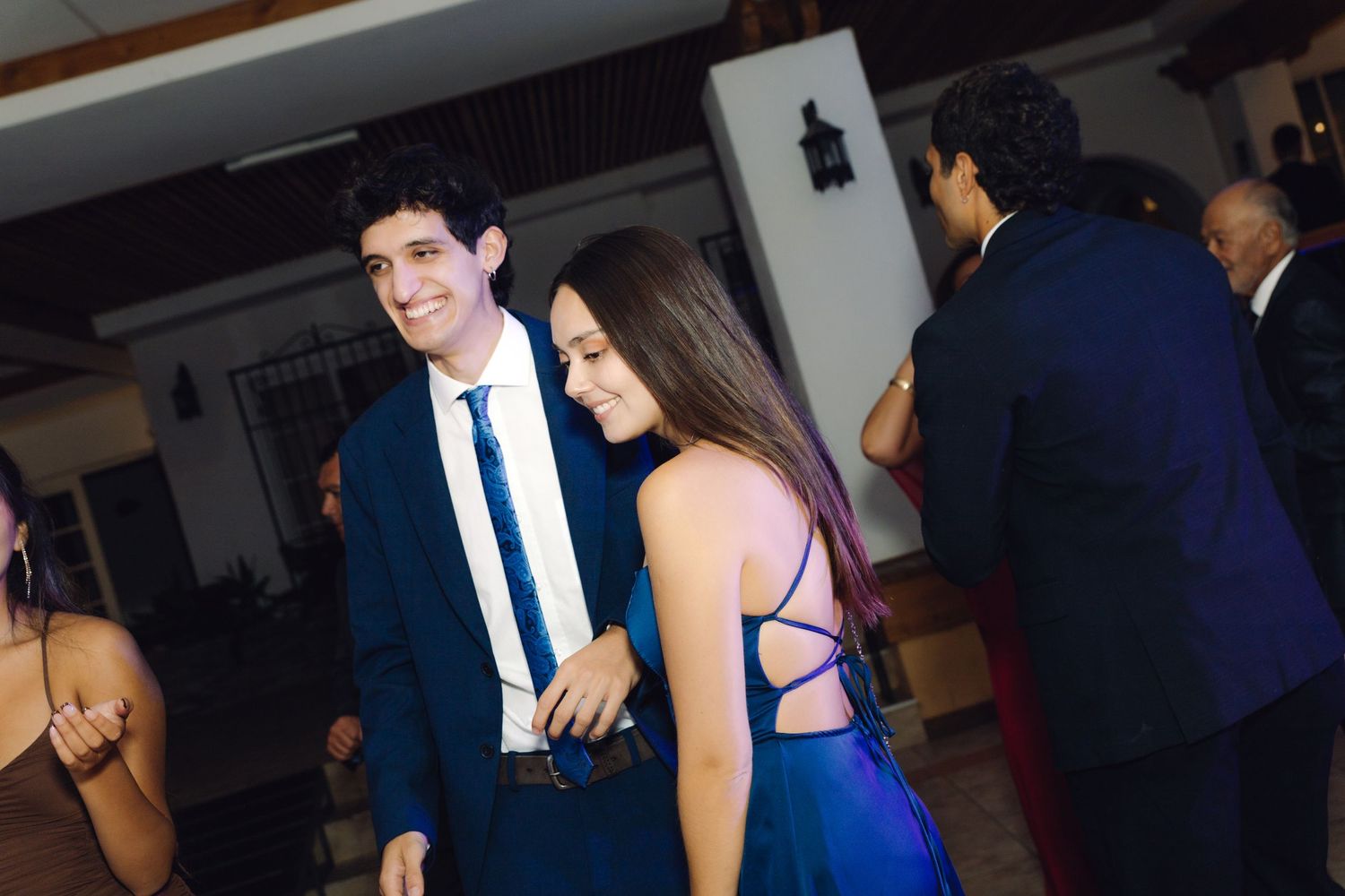 Young couple in formal attire smiling and chatting together at an elegant wedding reception.