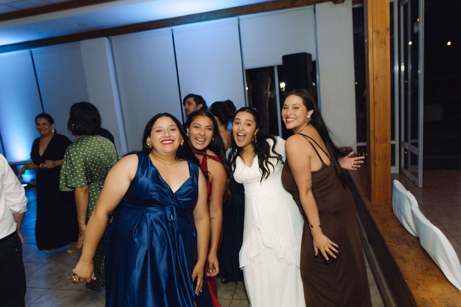 Bride poses and laughs with three bridesmaids on the dance floor at the wedding reception.