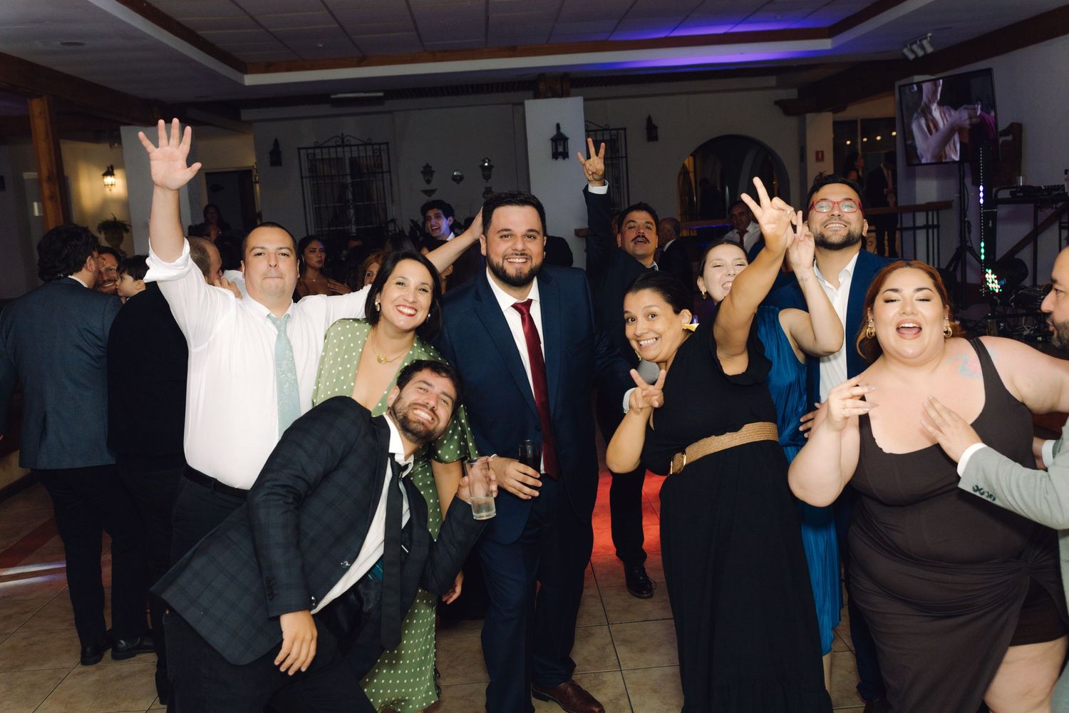 Groom and wedding guests strike fun poses together on the dance floor at the reception.