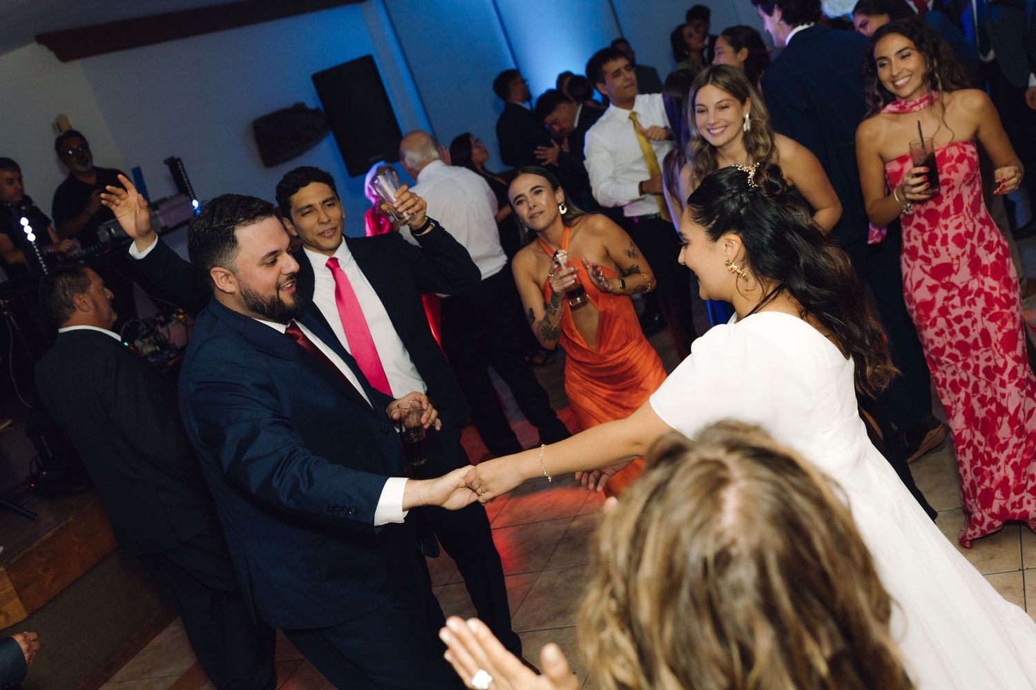 Bride and groom share a dance together surrounded by guests at their wedding reception.
