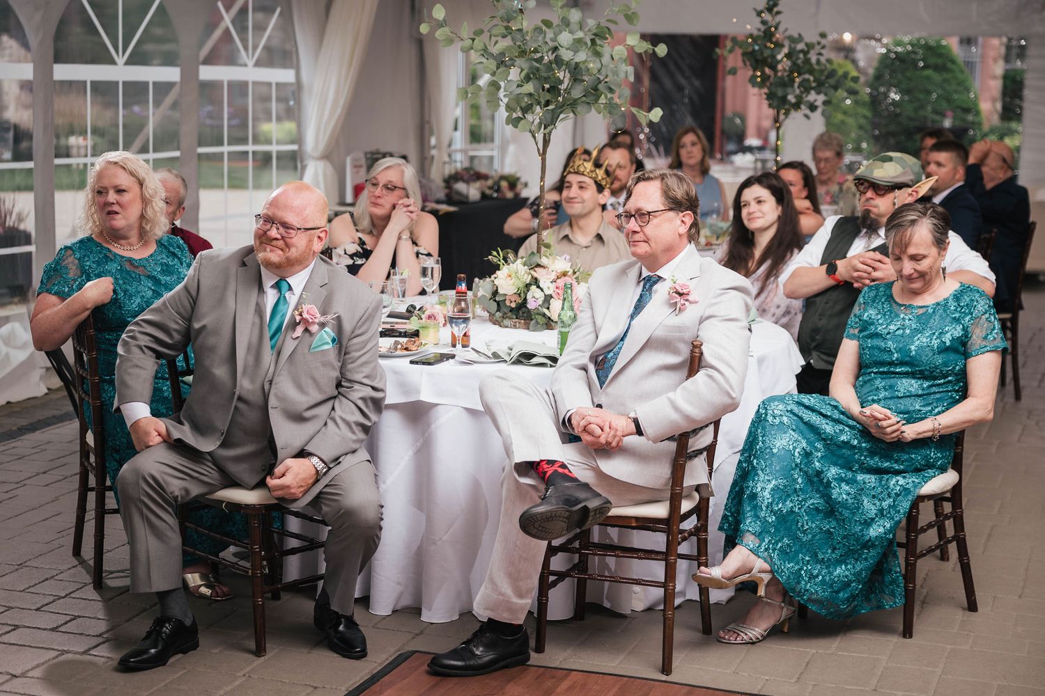Guests seated at a table listening and reacting during a speech at the reception.