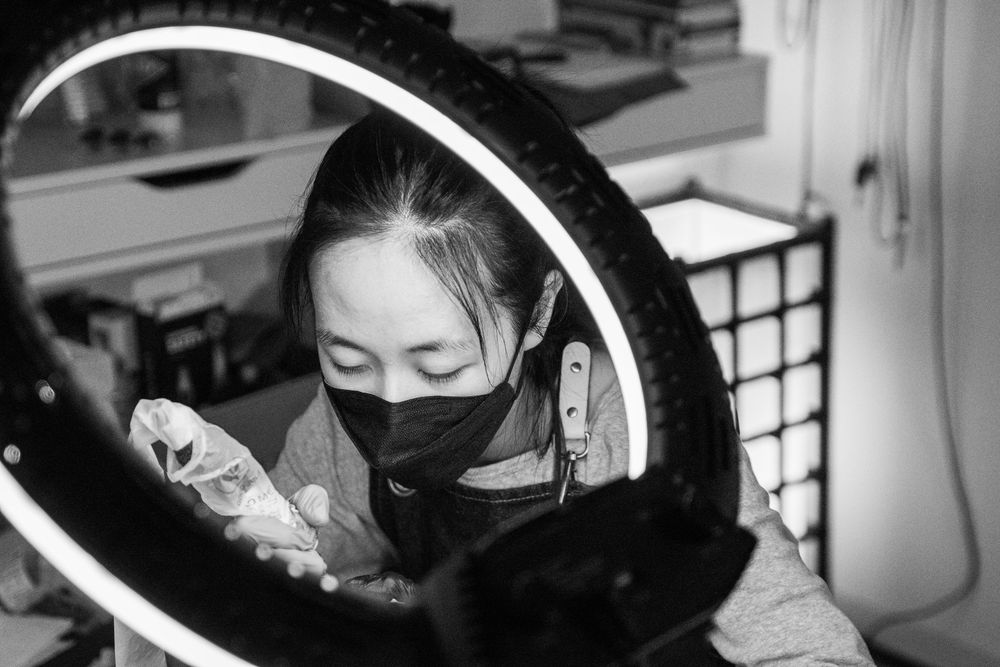 Black and white candid of tattoo artist working on wedding ring tattoo. Viewed through a light ring