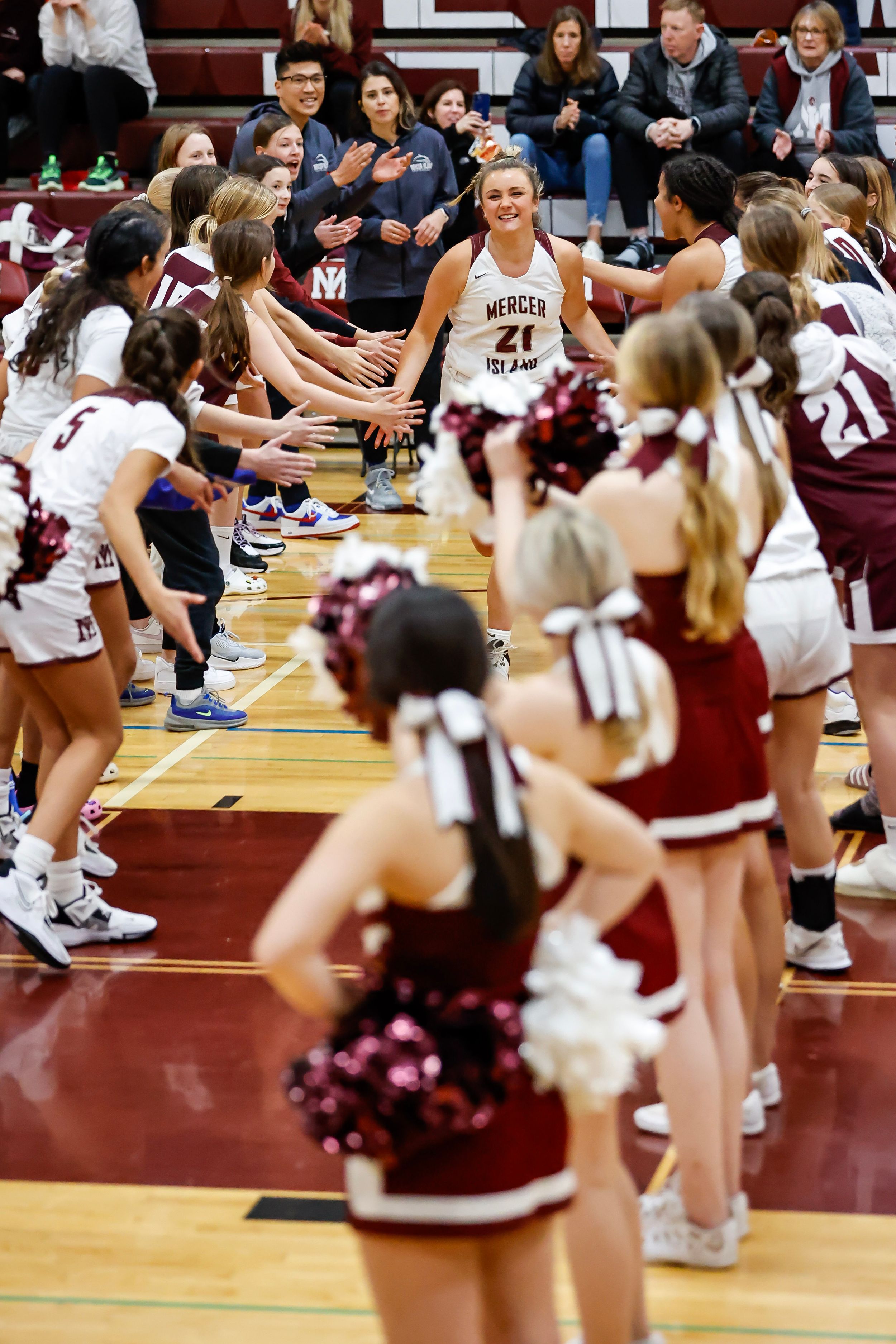 Girls high school basketball player introduced and runs through line of players.
