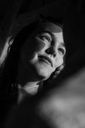 Dramatic black and white portrait of a young woman gazing upward with soft light on her face.