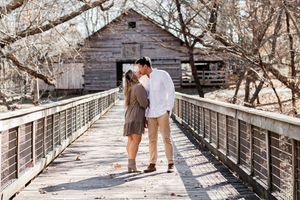 A couple shares a romantic moment on a wooden bridge walkway during winter.