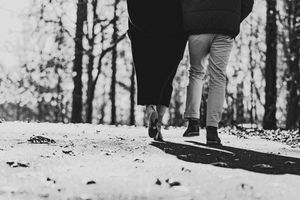 A black and white photo series showing legs and feet walking on a snowy path through a winter forest.