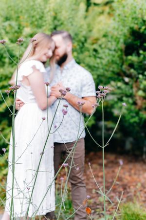 engaged couple faded on the background behind Purple flowers.
