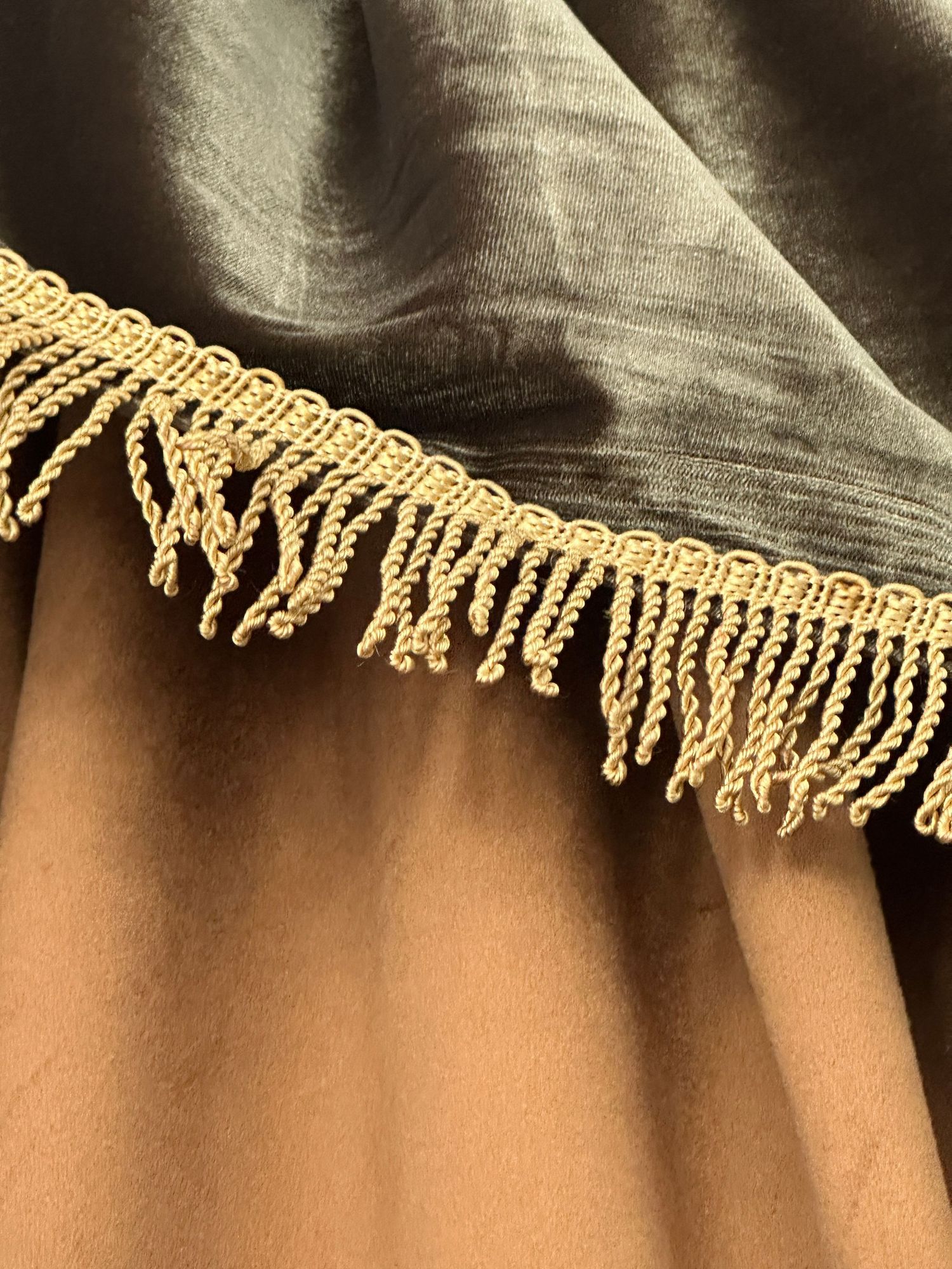 Gray velvet fabric with gold twisted fringe trim detail, elegant decorative textile border closeup.