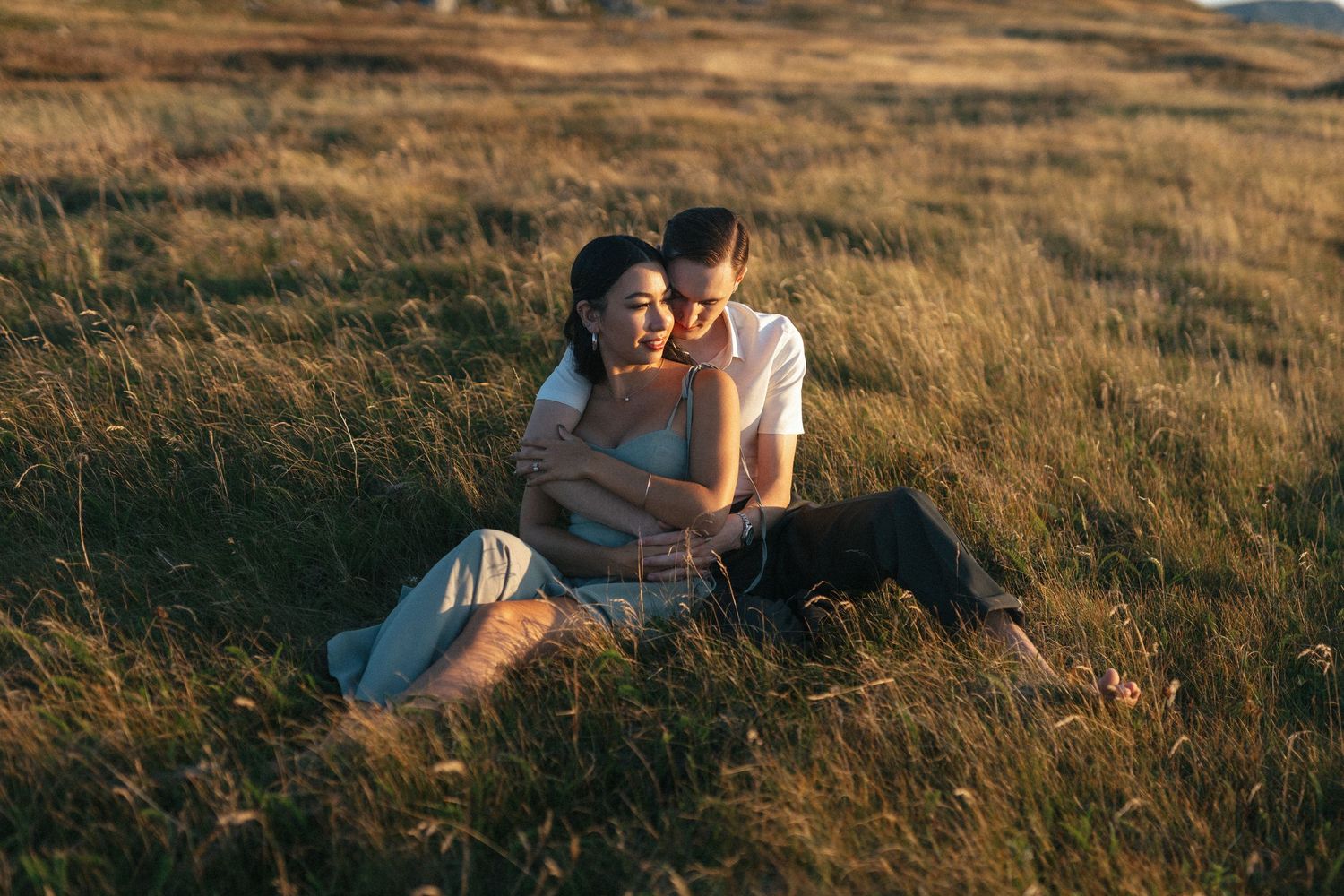 bride and groom cuddle in a field of tall grass at golden hour during Vancouver Island Elopement