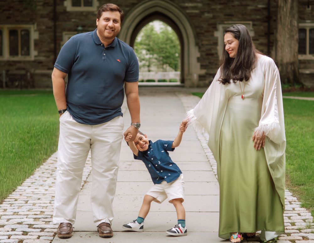 Expectant parents swinging their toddler son on a stone path, Princeton NJ maternity and family photography
