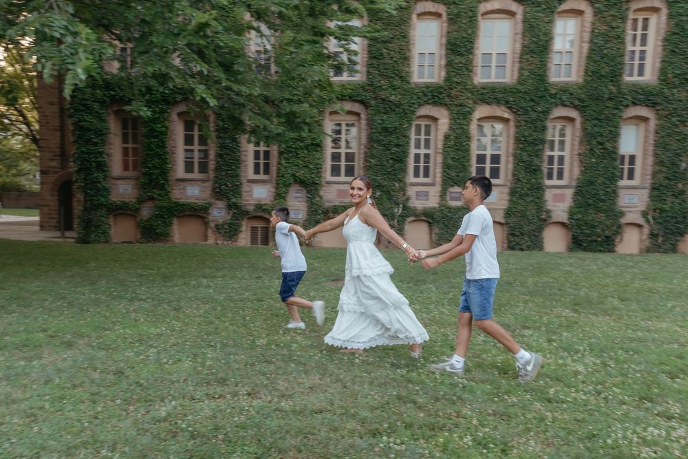Mom running across the grass with her sons in front of ivy walls, candid NJ family photography