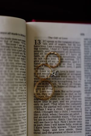 Wedding rings resting on an open Bible displaying 1 Corinthians 13, the love chapter.