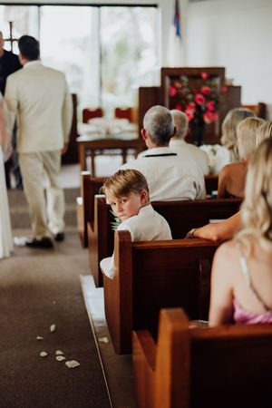 Young boy in church pew looking back during a wedding ceremony in a chapel.