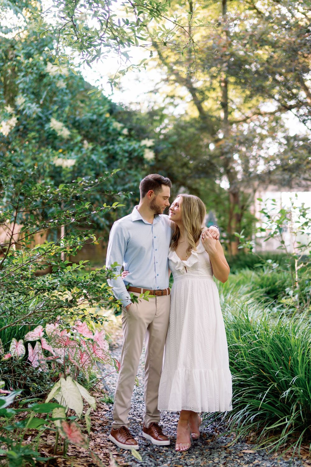 Couple in a lush garden, man in blue shirt and woman in white dress.