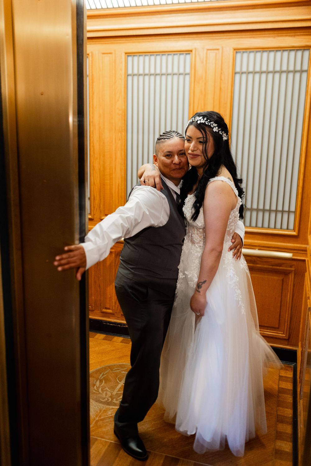 Bride and groom embracing in a wooden elevator, smiling together on their wedding day.