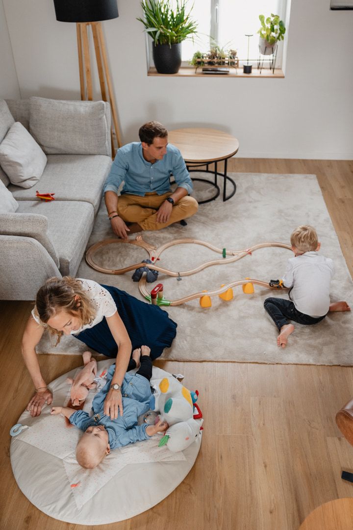 Papa au train avec le grand frere, maman sur le tapis d'eveil avec bebe, un moment capture par une photographe de famille a Lille
