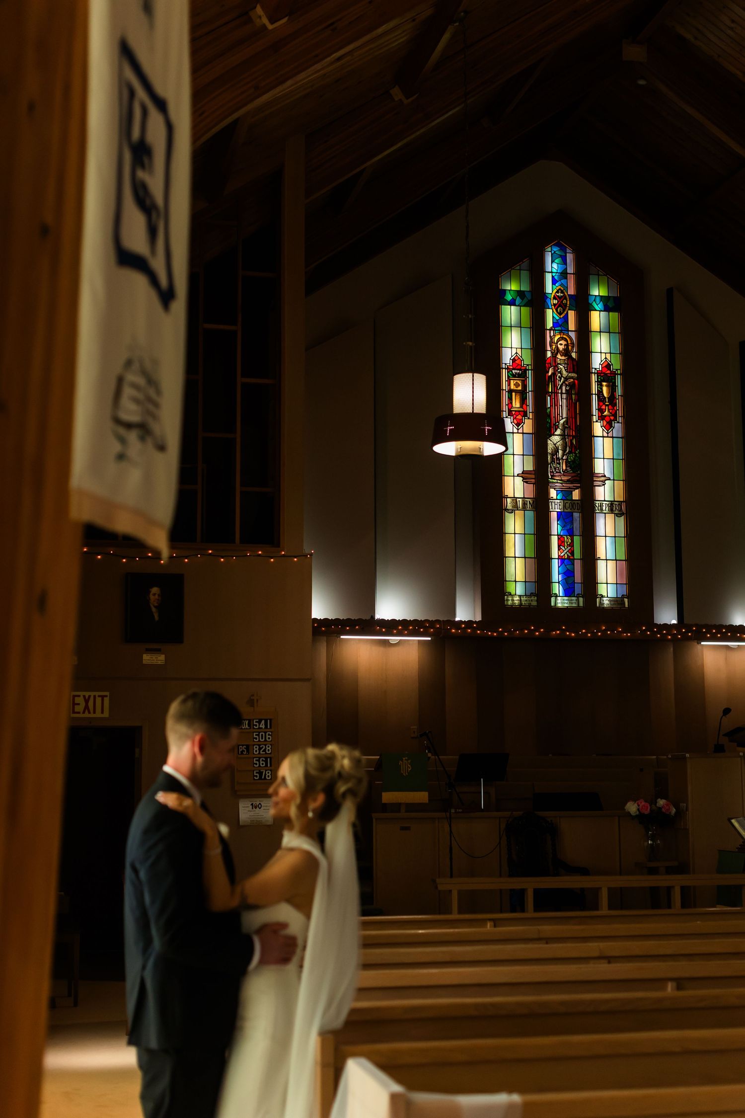Bride and groom share a romantic moment at the altar of a church with stunning stained glass windows during their wedding ceremony.