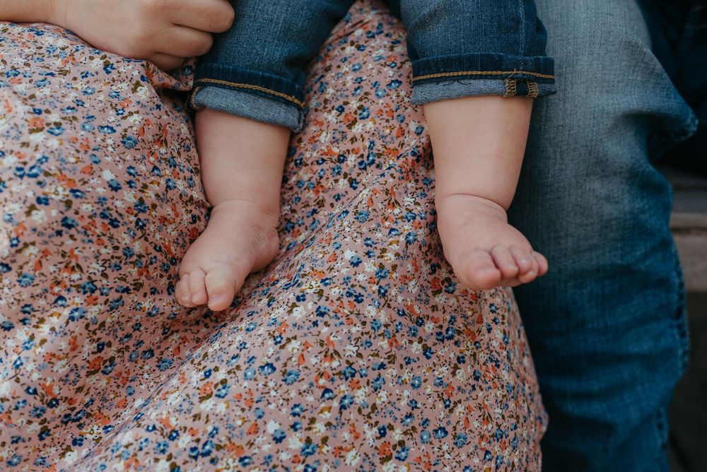 Close-up of tiny bare feet resting on a floral patterned fabric surface.
