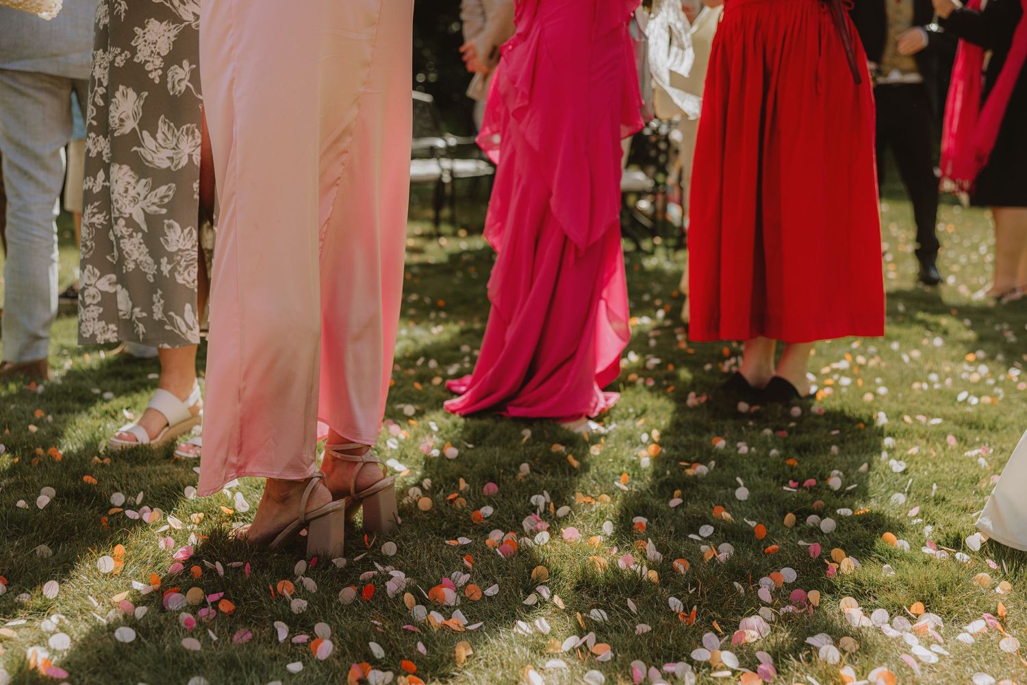 Wedding party in pink and red dresses standing together outdoors.