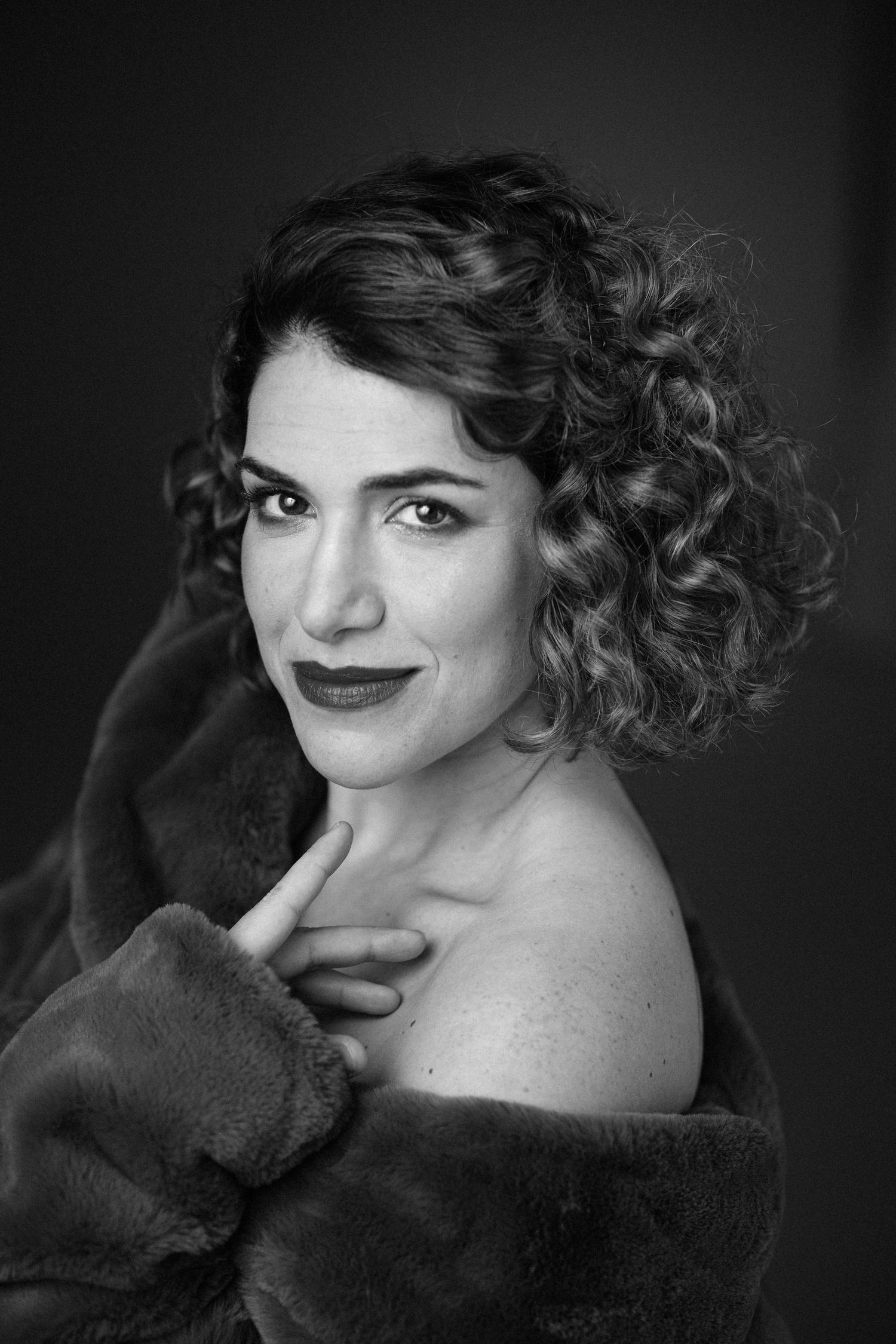 Dramatic monochrome portrait with vintage styling and dark fur wrap.