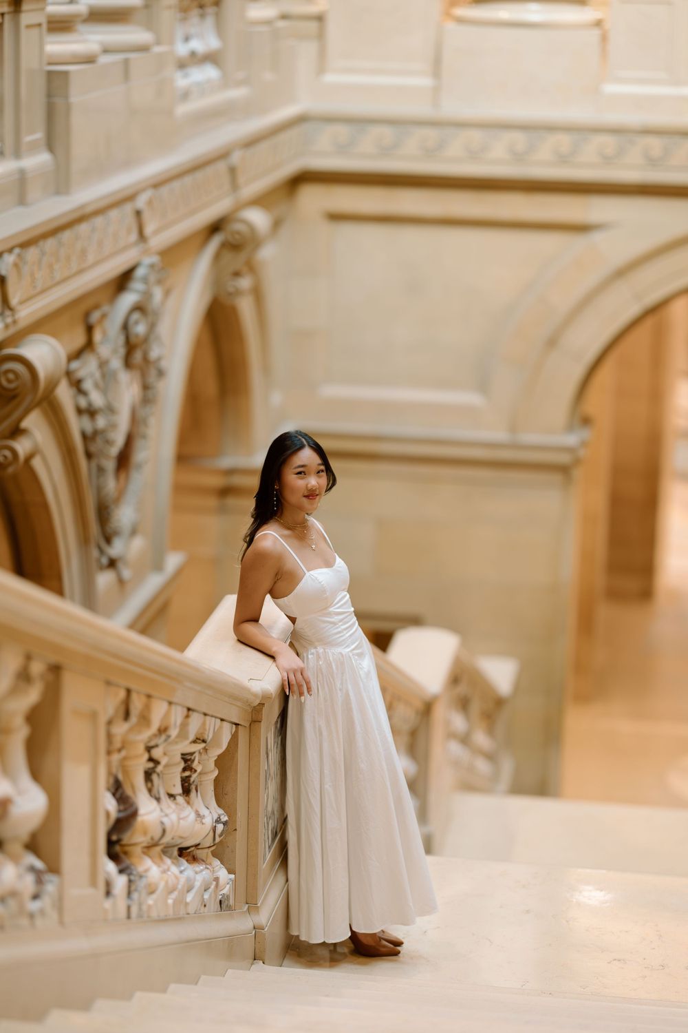 A serene portrait on an ornate marble staircase showcasing elegant classical architecture.