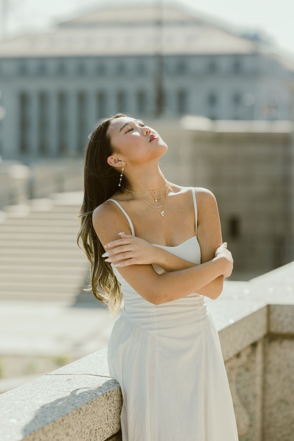 A dreamy outdoor portrait with sunlit architecture in the background.