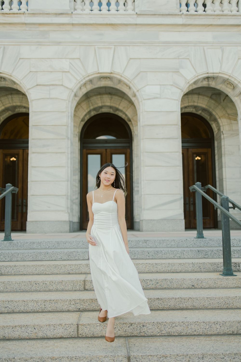 An ethereal portrait on classical stone steps with arched doorways in the background.