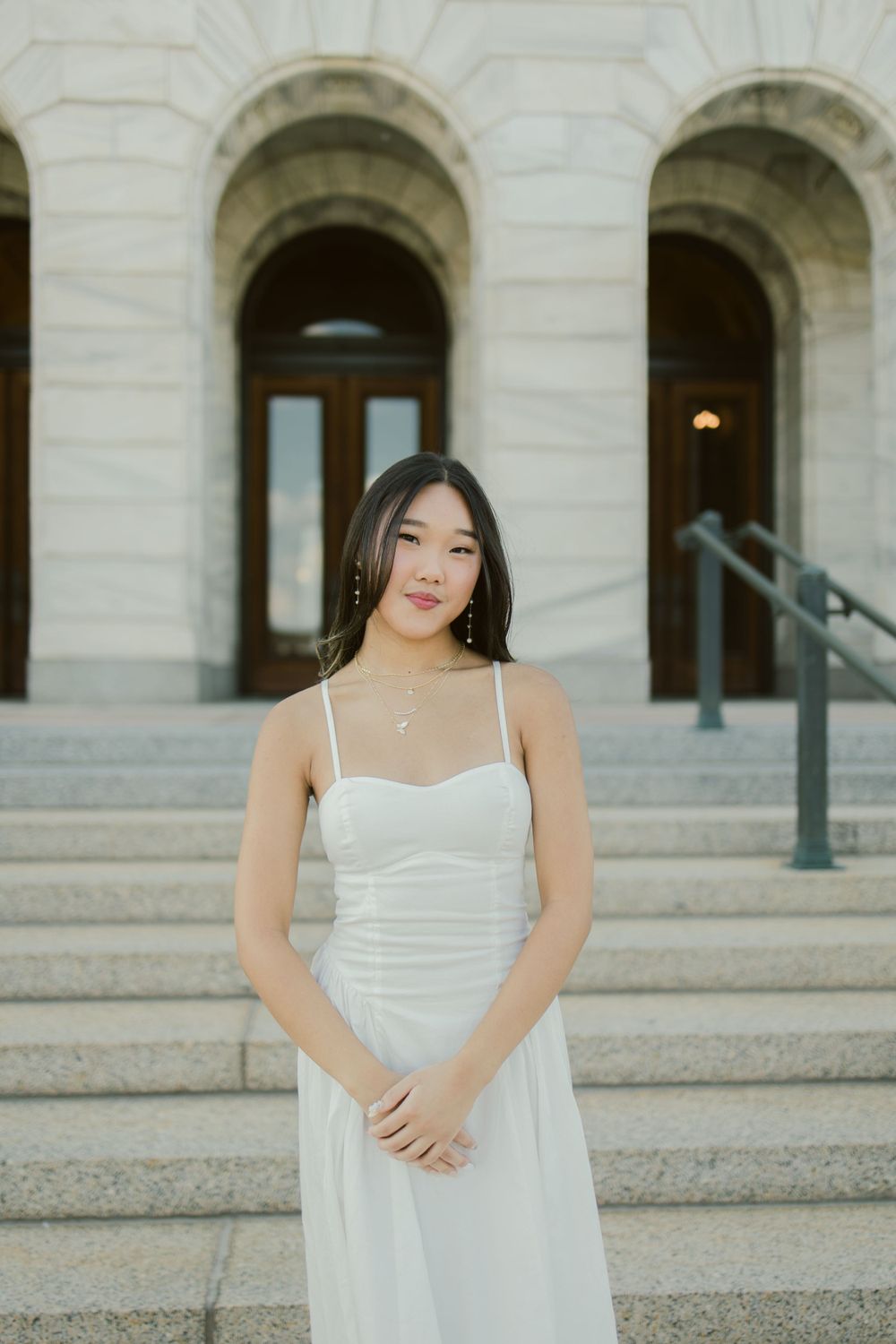 A white summer dress photographed against a grand building entrance with stone archways and steps.