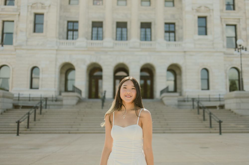 Elegant white dress captured in front of historic building with ornate stonework.