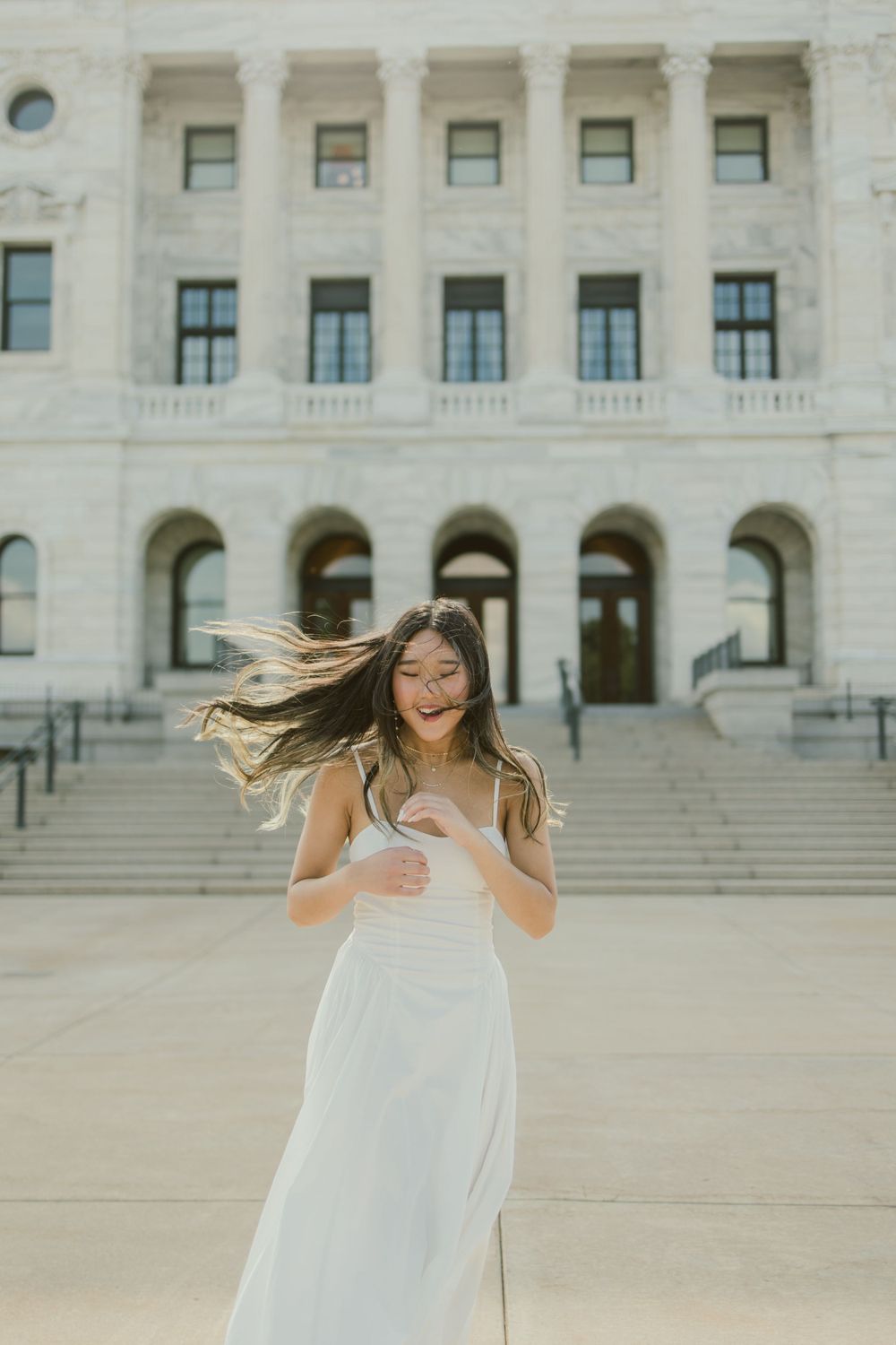 Wind-swept white dress moment captured against stone building facade.