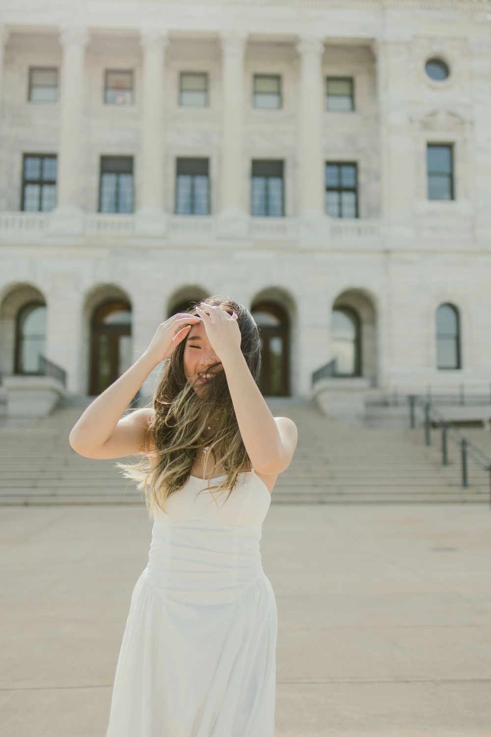 Playful summer dress portrait against architectural backdrop.
