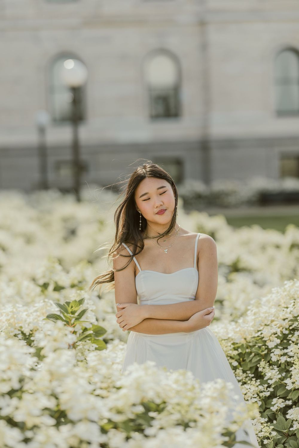 Ethereal spring portrait surrounded by white flowers and stone architecture.