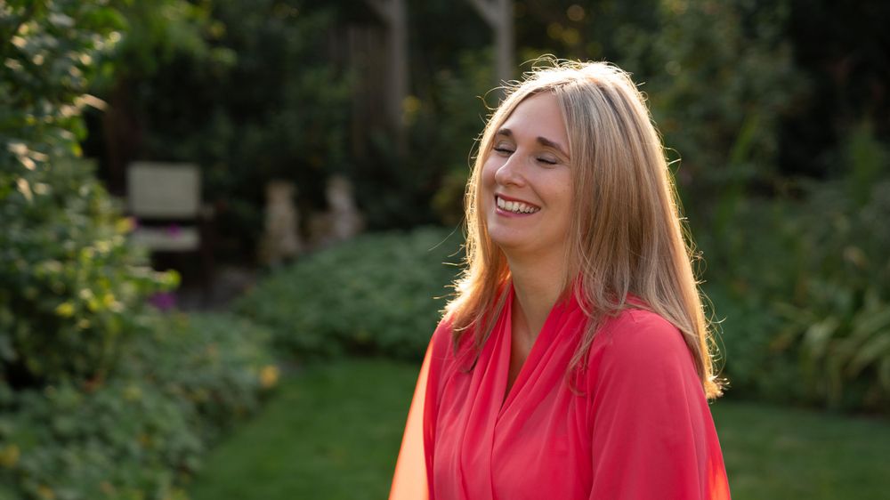 Portrait of a woman laughing in nature, with greenery in Zonhoven, exuding joy and natural beauty.
